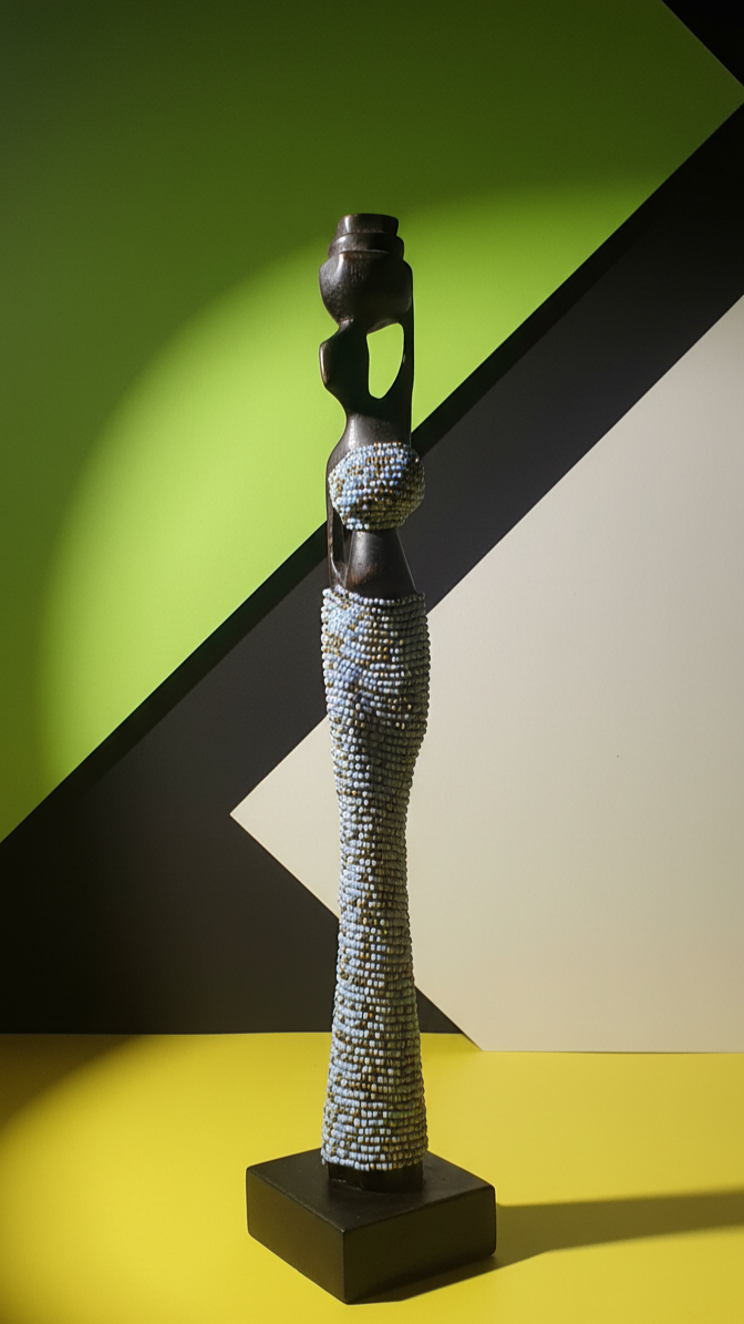 Decorative sculpture with mosaic design on a black base against a green and white geometric background