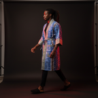 Person wearing a colorful robe walking against a dark background