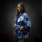 Woman wearing a blue tie-dye robe against a black background