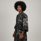 Person wearing a black and white patterned robe against a plain background