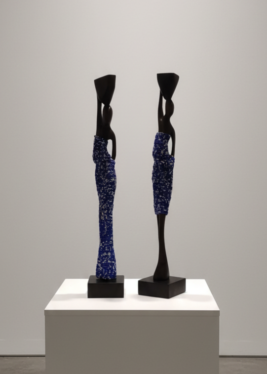 Two abstract sculptures on a white pedestal against a gray wall.