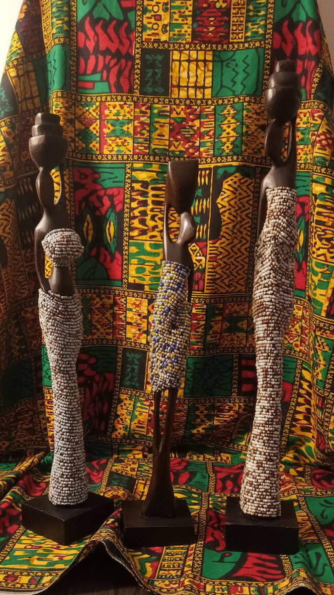 Three decorative figures on stands against a colorful patterned fabric background