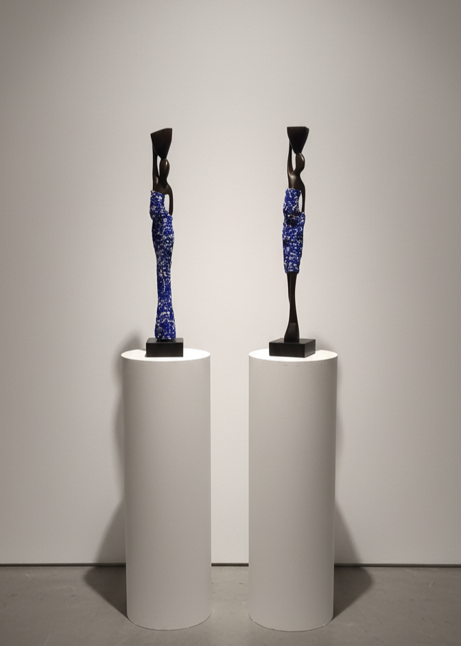 Two abstract sculptures on white pedestals against a gray background