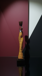 Decorative sculpture with textured surface on a reflective surface against a geometrically patterned wall.