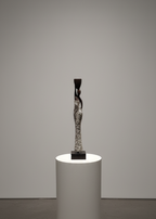 Abstract sculpture on a cylindrical white pedestal against a plain wall.