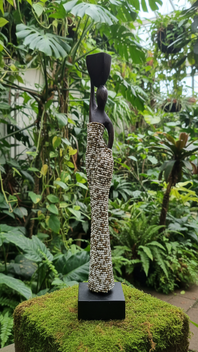 Statue of a woman on a moss-covered pedestal in a lush green garden