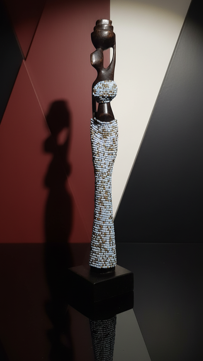 Decorative object with a textured base and a cylindrical top, set against a dark background.