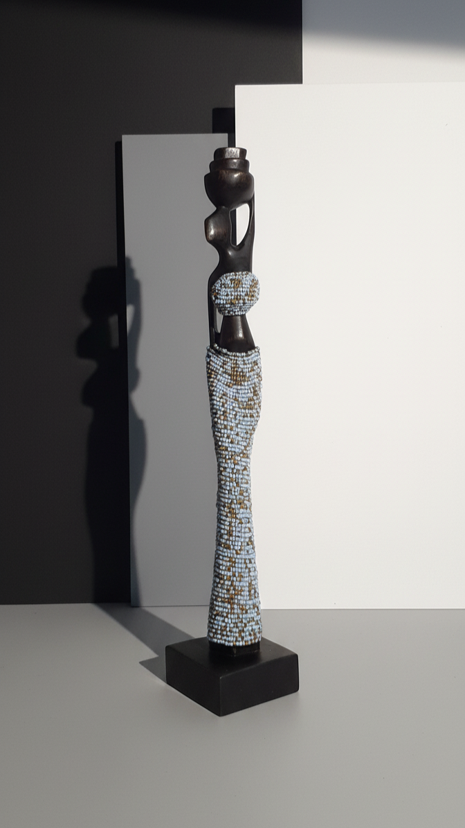 Decorative sculpture on a black stand against a gray background