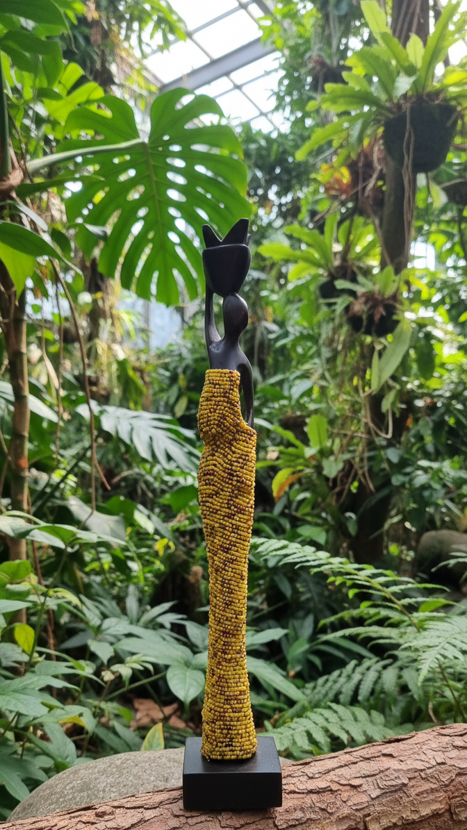 Decorative item with yellow textured object on a black stand against a natural background