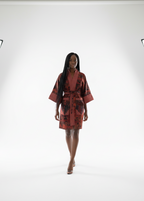 Model wearing a red and black patterned dress in a studio setting with lighting equipment.