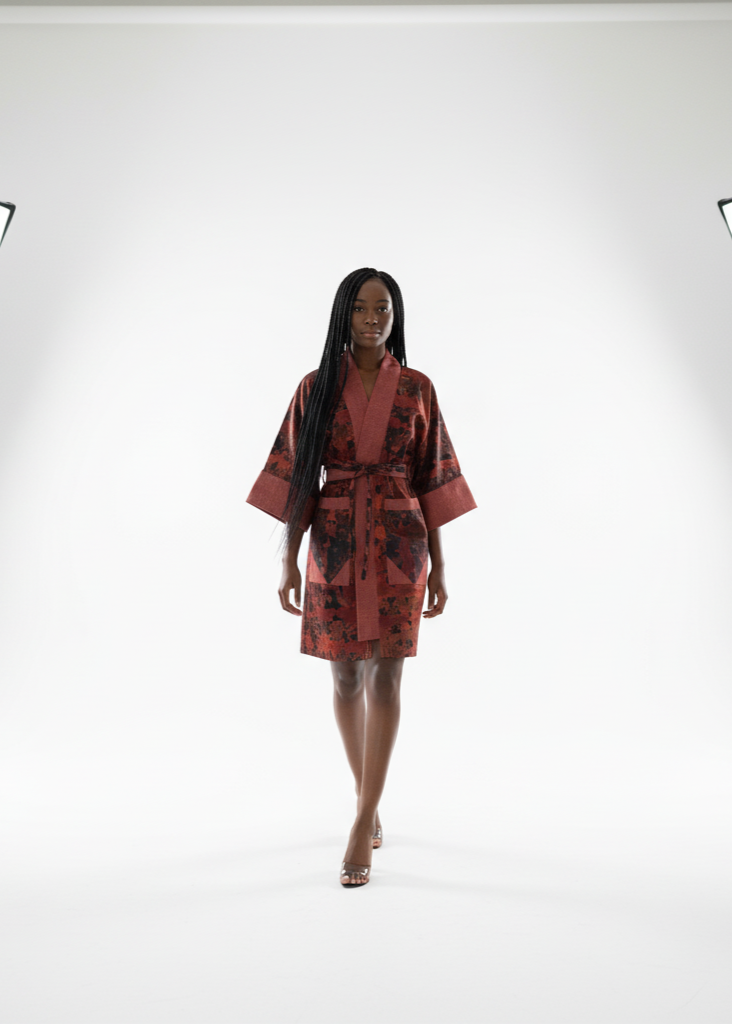 Model wearing a red and black patterned dress in a studio setting with lighting equipment.