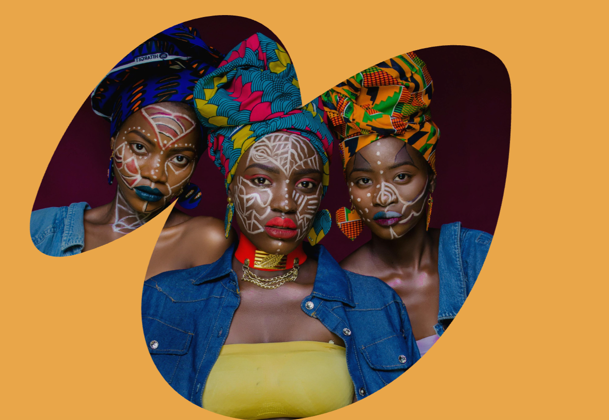 Three women with traditional makeup and headwraps on a yellow background